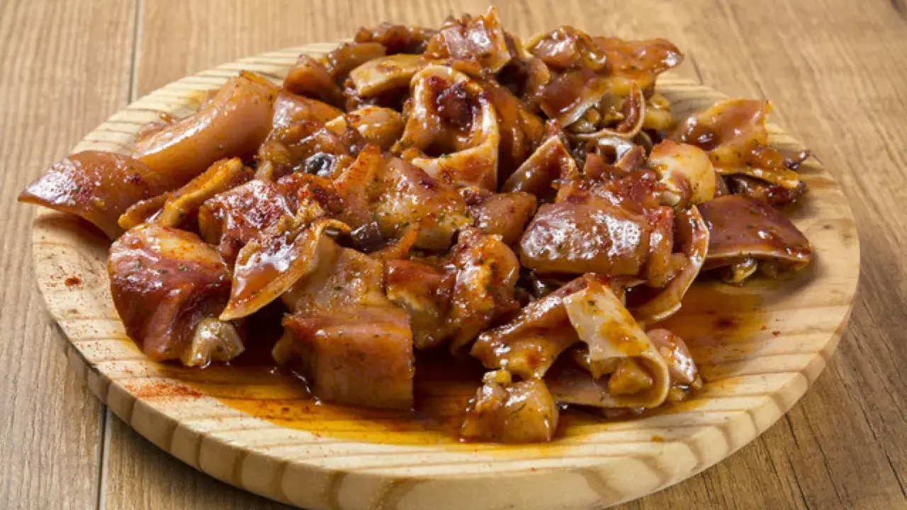 Oreja a la gallega, trozos de oreja de cerdo marinados y cocinados, servidos en una tabla de madera.