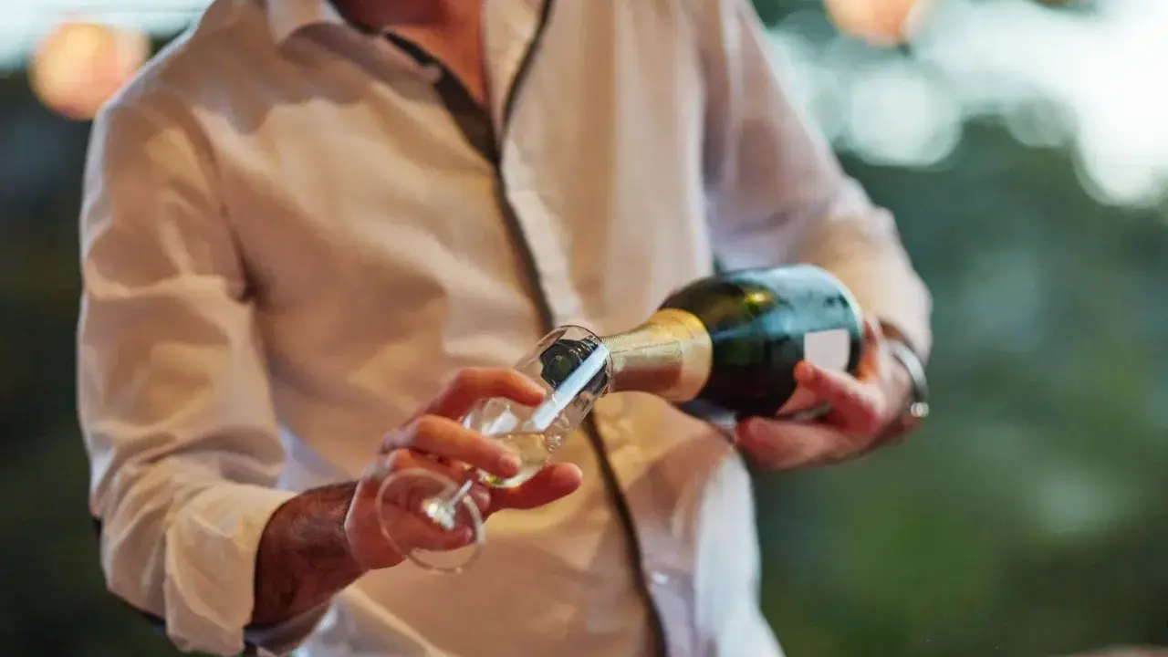 Un hombre sirve cava español en una copa.