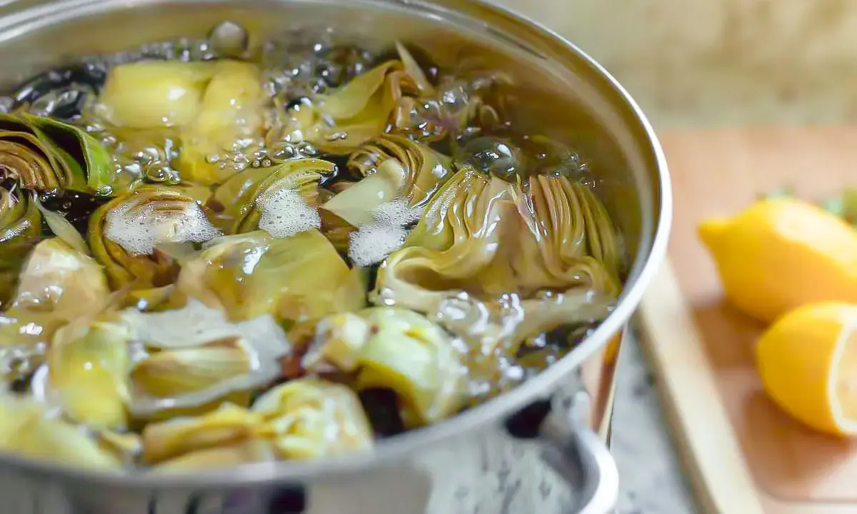 Alcachofas cortadas hirviendo en una olla. Aprende como cocer alcachofas para un plato delicioso.