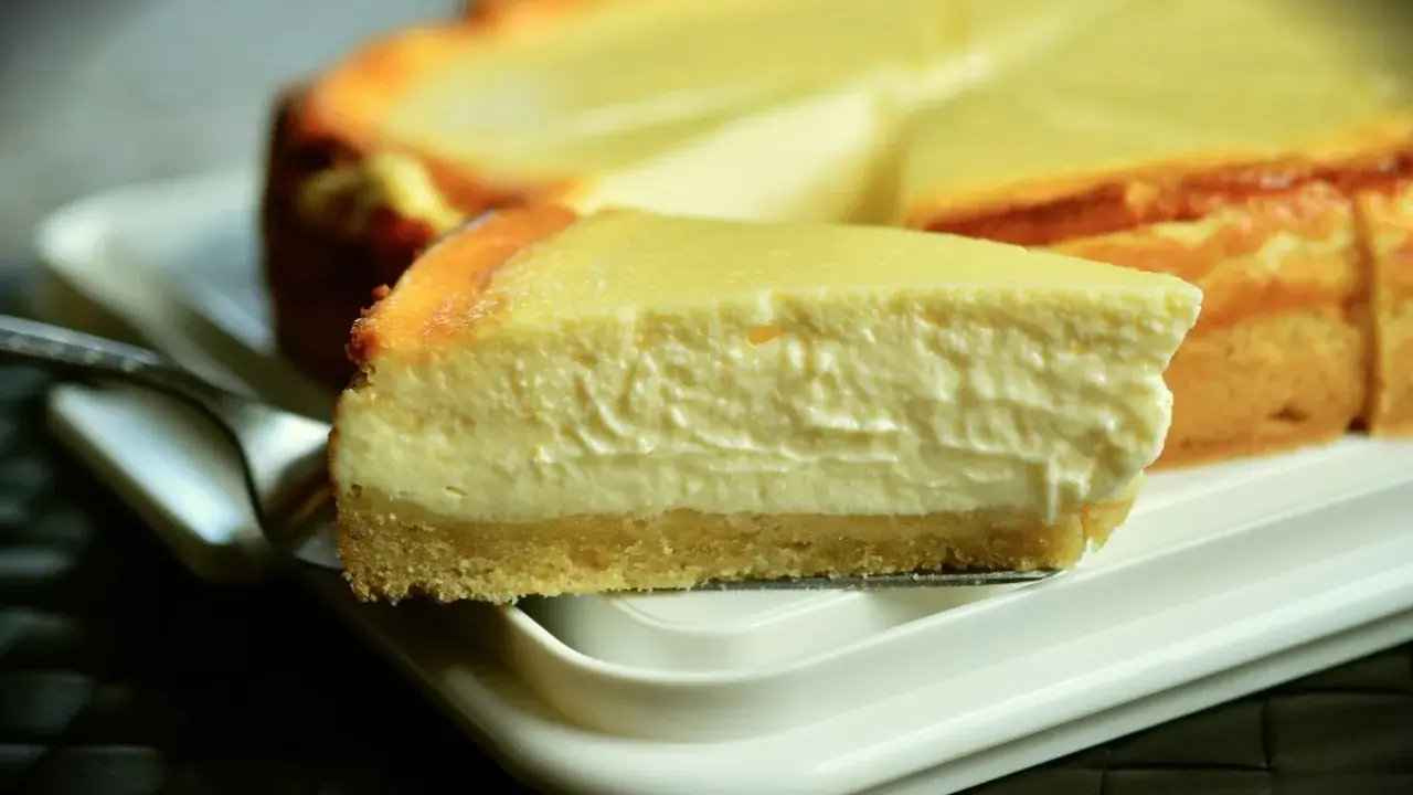 Una rebanada cremosa de tarta de queso Philadelphia, con su base dorada y relleno suave, lista para ser disfrutada.