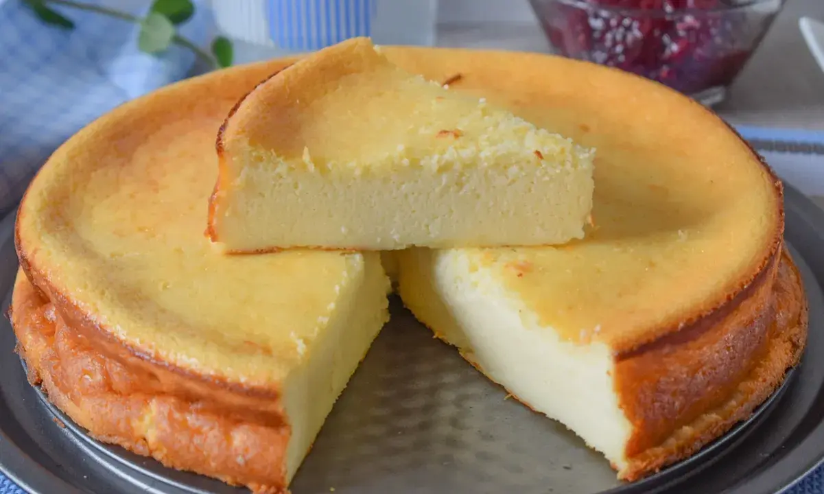 Una deliciosa tarta de queso recién horneada, con una rebanada servida encima. Perfecta para compartir.