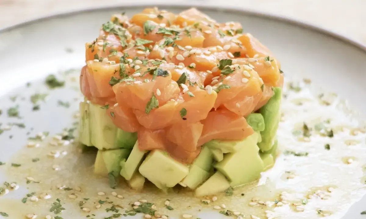 Delicioso tartar de salmón y aguacate, coronado con semillas de sésamo y perejil fresco.