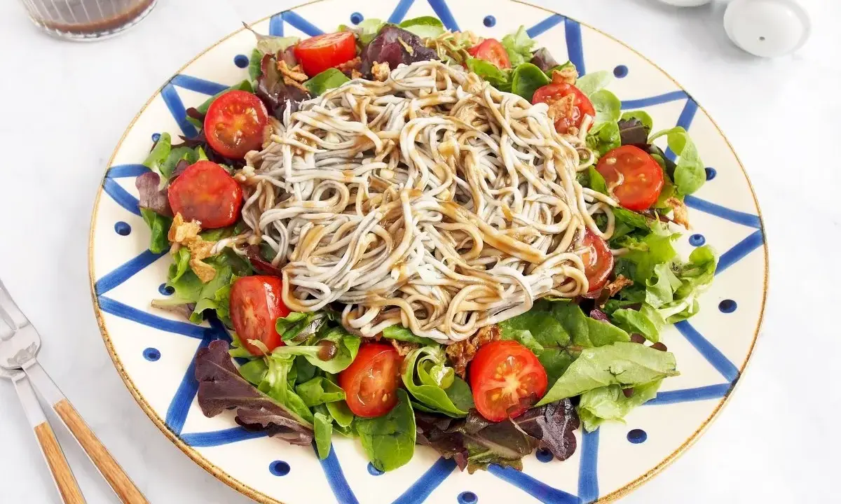 Deliciosa ensalada de gulas con tomates cherry y hojas verdes, servida en un plato decorado.