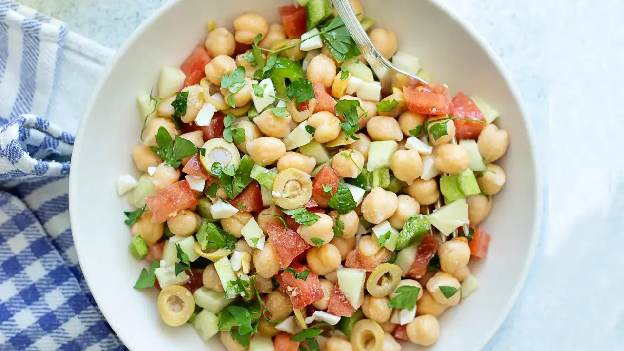 Ensalada garbanzos fresca con tomate, pepino, aceitunas y perejil. Un plato ligero y nutritivo.