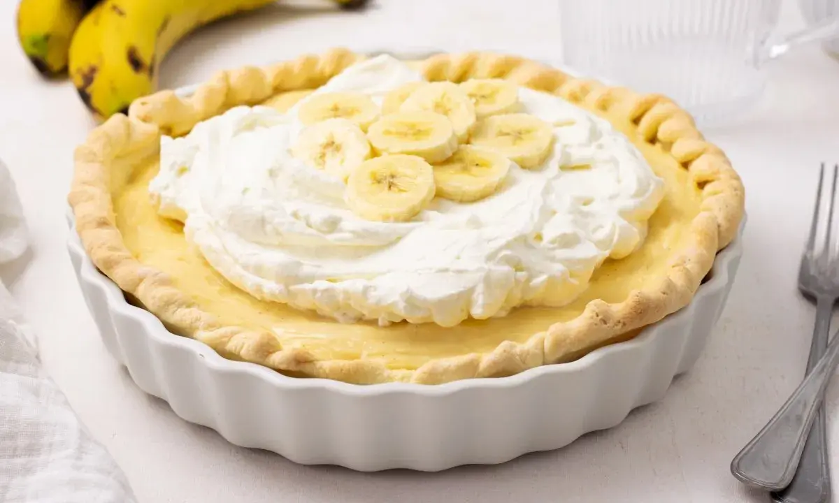 Deliciosa tarta de plátano con crema batida y rodajas de plátano fresco.