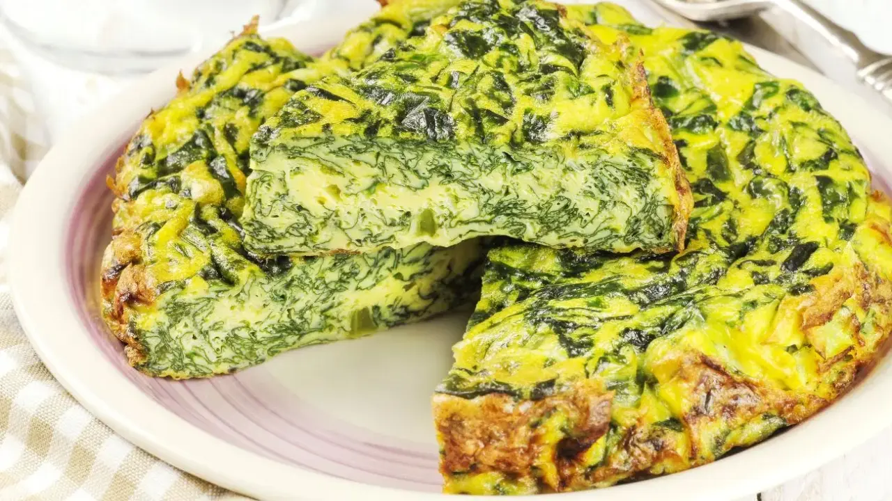 Tortilla de espinacas y queso, dorada y esponjosa, servida en un plato.