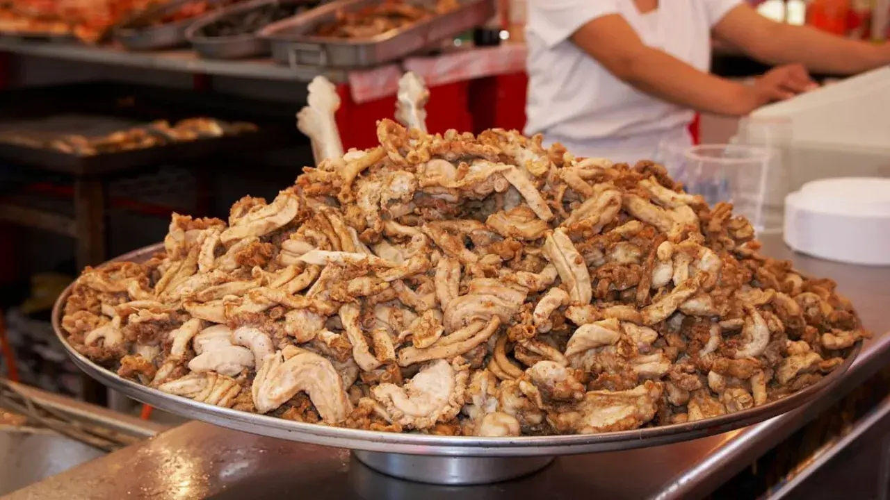 Montón de gallinejas y entresijos fritos, listos para servir en un puesto de comida callejera.