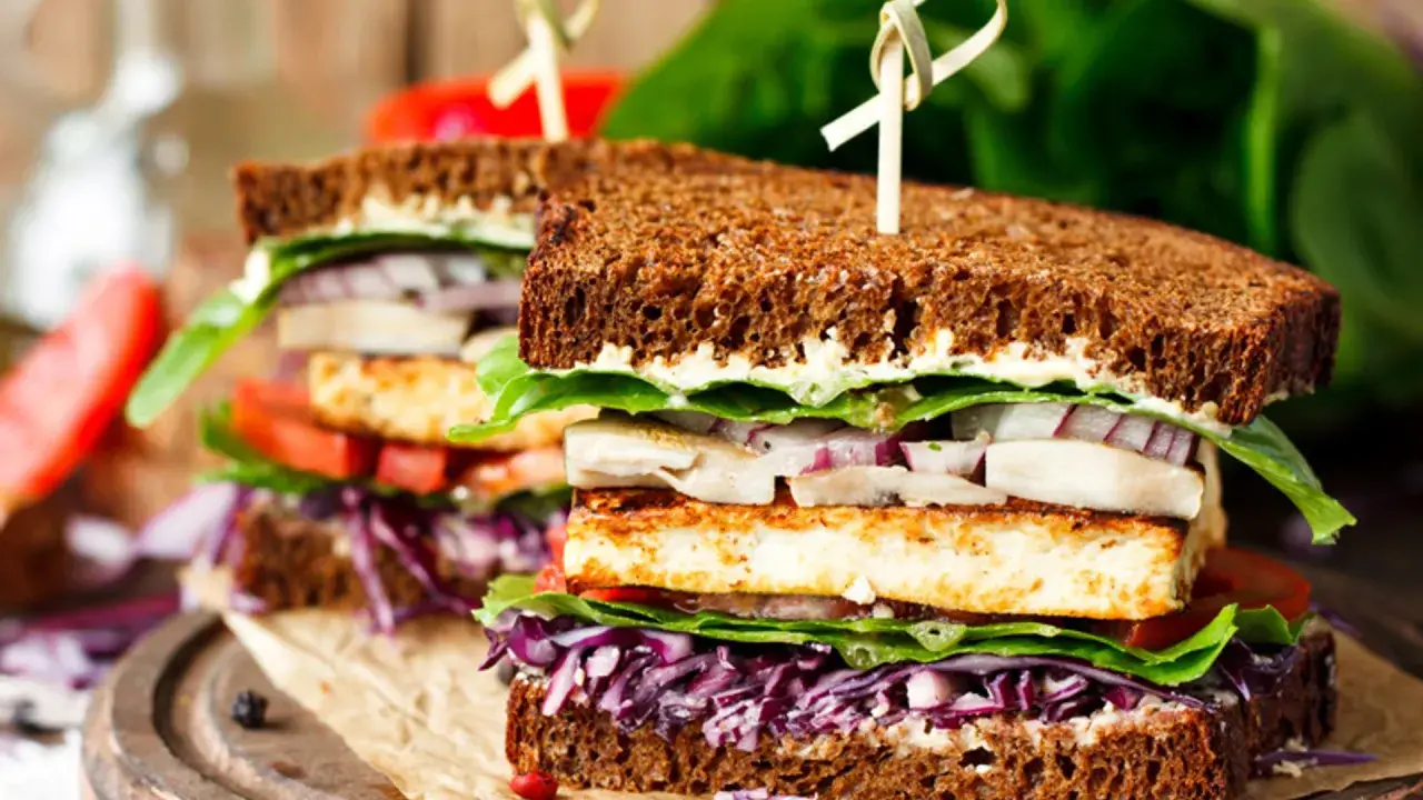 Delicioso sandwich vegetal con pan integral, tofu a la plancha, lechuga, tomate, cebolla morada y col lombarda.