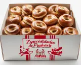 Caja llena de rosquillas de palo doradas y brillantes, listas para ser disfrutadas.