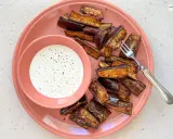 Berenjenas en freidora de aire, doradas y crujientes, servidas con una cremosa salsa blanca. ¡Un aperitivo delicioso!