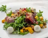 Deliciosa ensalada de cecina con mango, queso de cabra y nueces sobre rúcula fresca.
