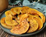 Rodajas de calabaza a la plancha, doradas y sazonadas con hierbas, servidas en un plato azul.