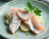 Lubina a la sal Thermomix: jugosos filetes de pescado sobre patatas, decorados con perejil fresco y un toque de aceite.