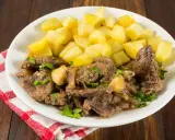 Plato de higaditos de pollo en salsa con patatas fritas en cubos, decorado con perejil fresco.