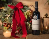 Botella de vino tinto fino Emilio Moro junto a un arreglo floral navideño, vela encendida y un candelabro dorado.