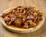 Oreja a la gallega, trozos de oreja de cerdo marinados y cocinados, servidos en una tabla de madera.