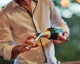 Un hombre sirve cava español en una copa.