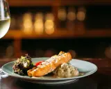 Un filete de salmón a la parrilla con ensalada y una copa de vino blanco, perfecto para un maridaje con riesling.