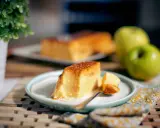 Un delicioso flan de manzana, con una porción servida en un plato, acompañado de manzanas verdes y una planta decorativa.