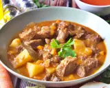 Un reconfortante plato de patatas guisadas con trozos de carne tierna, zanahorias y patatas en una rica salsa.