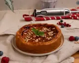Bizcocho de avena casero, glaseado y decorado con piñones y menta. Frutos rojos y batidora al fondo.