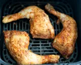 Muslos de pollo dorados y jugosos en la freidora de aire, listos para disfrutar.