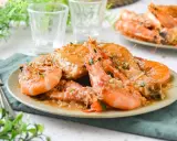 Plato de pollo con gambas en salsa, decorado con perejil picado. Se ve delicioso y listo para disfrutar.