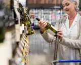 Mujer mayor elige una botella de vino español en el supermercado.