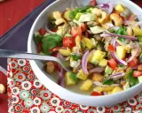 Un refrescante ceviche de berberechos con trozos de mango, aguacate, tomate y cebolla morada, servido en un cuenco blanco.