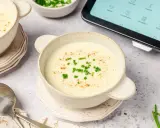 Crema de patatas y puerros lista en la vichisua Thermomix, servida en cuencos con cebollino y pimentón.