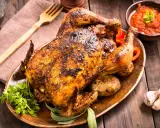 Un delicioso pollo al horno crujiente y jugoso, servido con patatas asadas, pimientos rojos y salsa. ¡Perfecto para una comida familiar!