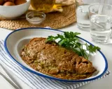 Tortilla de alcachofas dorada y jugosa, servida en plato blanco con borde azul. Decorada con perejil fresco.