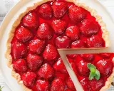 Deliciosa tarta de fresas cubierta con gelatina brillante y fresas frescas. Una porción se ha cortado, revelando la jugosa fruta.