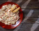 Ensaladilla rusa cremosa en plato rojo, con palitos de pan. ¿Cuanto dura la ensaladilla rusa en la nevera?
