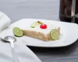 Deliciosa carlota de limón, con galletas y crema, decorada con rodajas de lima y una cereza.