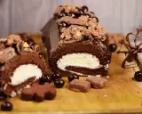 Delicioso rollo de chocolate cubierto con crema y decorado con más chocolate y dulces.