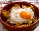 Un plato de patatas fritas con pimientos y un huevo estrellado encima, listo para disfrutar.