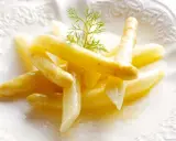 Espárragos blancos tiernos, listos para cocinar, servidos en un plato blanco con una ramita de eneldo.