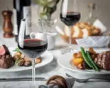 Dos copas de vino tinto, filetes jugosos y patatas asadas, perfectos para una cena de vino de invierno.