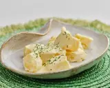 Patatas alioli cremosas y deliciosas, cubiertas con perejil fresco picado, servidas en un cuenco rústico sobre un salvamanteles verde.