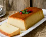 Delicioso budín de pan con caramelo dorado, decorado con frutos rojos y menta. Una rebanada ya servida.