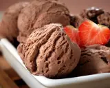 Cucharadas de cremoso helado de chocolate, decoradas con fresas frescas, listas para disfrutar.