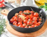 Tomates cherry confitados en sartén de hierro fundido, con ajo y hierbas aromáticas.