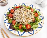 Deliciosa ensalada de gulas con tomates cherry y hojas verdes, servida en un plato decorado.