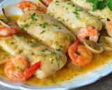 Merluza a la marinera con gambas y almejas, un plato delicioso bañado en salsa.