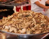 Montón de gallinejas y entresijos fritos, listos para servir en un puesto de comida callejera.