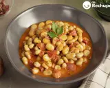 Plato de habas con jamón, guisadas en una salsa rojiza y decoradas con perejil.