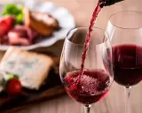 Vino tinto servido en copas, con tabla de quesos y embutidos al fondo. Una cata para apreciar la diferencia entre tempranillo y crianza.