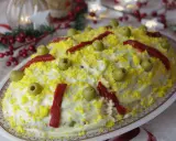 Ensaladilla rusa, la receta de la abuela, cubierta de mayonesa, huevo rallado, aceitunas y pimientos. ¡Un clásico festivo!