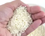 Mano sosteniendo arroz, una medida aproximada de cuanto arroz por persona para una comida deliciosa.